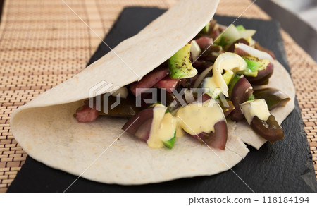 Salad of black tomatoes, avocado and onions in Italian tortilla on black stone board Salad of black tomatoes, avocado and onions in Italian tortilla on black stone board 118184194