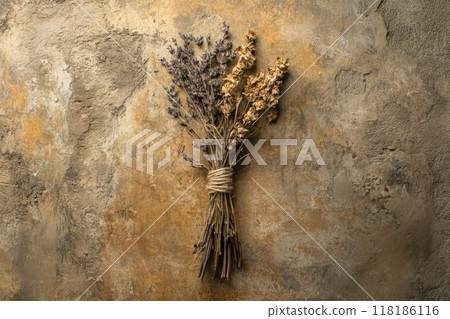 An intricate arrangement of dried herbs is skillfully tied together with twine, showcasing natural textures against a rustic, earthy backdrop. This composition emphasizes simplicity and beauty. 118186116