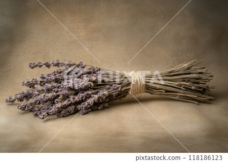 A beautifully arranged bundle of dried lavender sits quietly, wrapped in rustic twine against a soft, muted backdrop. Its delicate blossoms evoke a sense of tranquility and nostalgia. 118186123