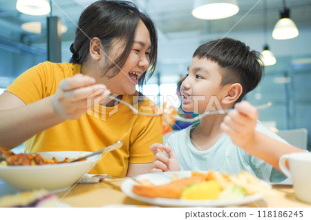 Single mom family lifestyle, mother and son are having a lunch together at fast food restaurant. Single mom family lifestyle, mother and son are having a lunch together at fast food restaurant. 118186245