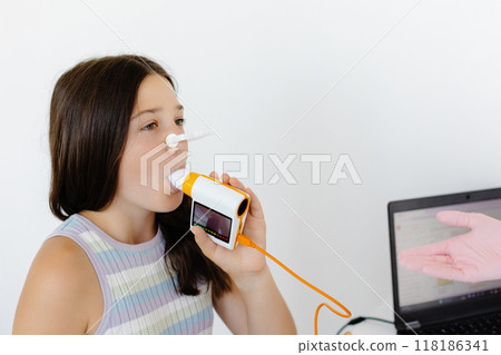 Girl testing breathing function by spirometry in doctors office. Diagnosis of respiratory function in pulmonary disease Girl testing breathing function by spirometry in doctors office. Diagnosis of respiratory function in pulmonary disease 118186341