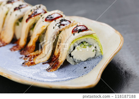 Eel sushi roll with creamy filling, topped with savory sauce and sesame seeds on a stylish plate Eel sushi roll with creamy filling, topped with savory sauce and sesame seeds on a stylish plate 118187188