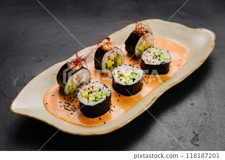 Sushi rolls on spicy sauce garnished with sesame and chili threads for an exquisite presentation 118187201