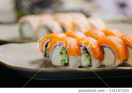 Assorted sushi rolls on plates in a restaurant setting, highlighting a variety of fresh ingredients 118187203