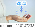 A hand holding a blue and white sign that says 2025 with three upward arrows 118187238