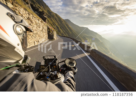 Motorbiker riding in Italian Alps during sunrise, handlebar view, dramatic sky. Travel and freedom, outdoor activities Motorbiker riding in Italian Alps during sunrise, handlebar view, dramatic sky. Travel and freedom, outdoor activities 118187356