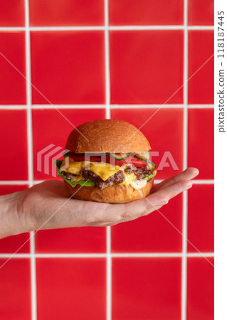 Cheeseburger on hand with red tile cafe background 118187445