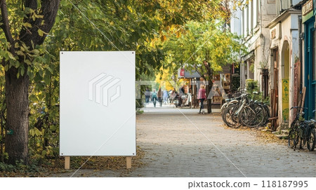 Small town street with a white blank sandwich board, artisan shop, bicycles, and a calm atmosphere, ideal for local advertising. Empty sandwich board 118187995