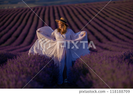 woman poses in lavender field at sunset. Happy woman in white dress holds lavender bouquet. Aromatherapy concept, lavender oil, photo session in lavender woman poses in lavender field at sunset. Happy woman in white dress holds lavender bouquet. Aromatherapy concept, lavender oil, photo session in lavender 118188709