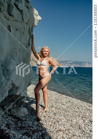 A woman is standing on a beach with her back to the camera 118188803