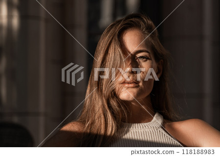Woman Portrait Sunlight Closeup - A woman with long brown hair sits in the sunlight with her face partially obscured by her hair. 118188983