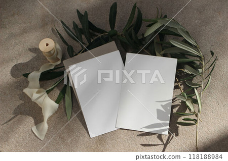 Mediterranean summer wedding stationery. Birthday mock-ups. Set of blank greeting cards, envelope. Grunge limestone floor background. Silk ribbon. Olive tree branches in sunlight. Flatlay, top 118188984