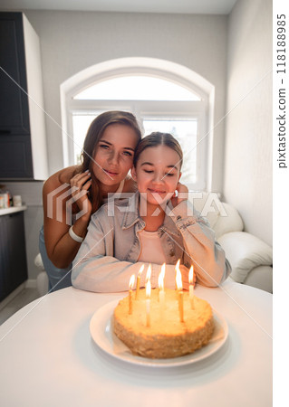 Birthday Cake Mom Daughter Celebration - Two women celebrate a birthday with a cake and candles at home. 118188985