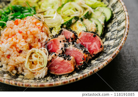 Healthy poke bowl with seared tuna, rice, seaweed salad, fresh vegetables - vibrant and nutritious 118191085