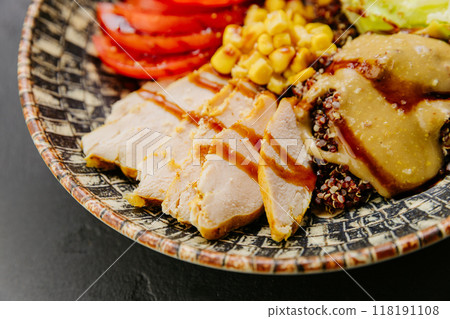 Healthy quinoa bowl with chicken, vegetables, beans, and dressing for a nutritious and balanced meal 118191108