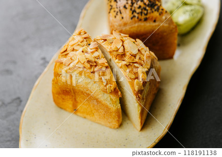 Freshly baked artisan bread slices with almonds and seeds, served with herbed butter on a plate Freshly baked artisan bread slices with almonds and seeds, served with herbed butter on a plate 118191138