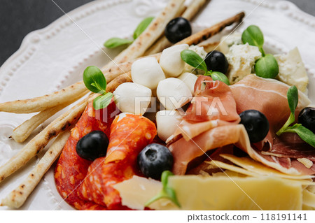 Italian antipasto platter with cured meats, cheese, olives, breadsticks, and fresh herbs Italian antipasto platter with cured meats, cheese, olives, breadsticks, and fresh herbs 118191141