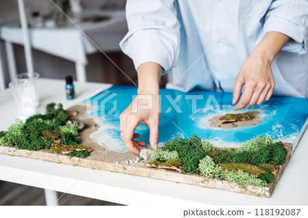 Creating a stunning epoxy resin art piece with a coastal landscape during a DIY project in a bright studio 118192087