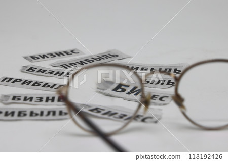 Glasses on the background of newspaper clippings with the words business and profit in Russian Glasses on the background of newspaper clippings with the words business and profit in Russian 118192426
