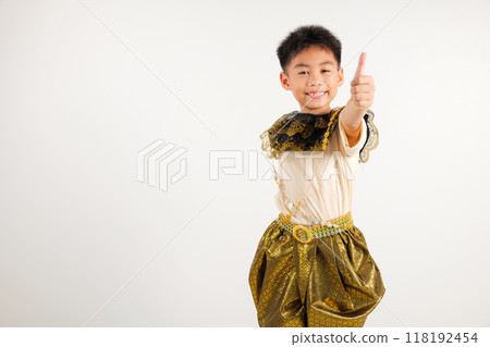 Portrait Thailand kid boy smiling traditional Thai dress costume makes thumbs up OK sign, symbolizing agreement, studio isolated white background, primary child radiates positivity and satisfaction 118192454