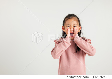 Asian happy portrait cute young kid girl standing hand on mouth talking news announcement studio shot isolated on white background, Thai kindergarten child announcement 118192458
