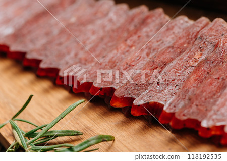 Sliced gourmet smoked salami on a wooden board with herbs, perfect for charcuterie boards and snacks 118192535