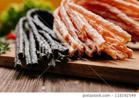 Variety of black and light meat sticks on board with herbs and spices, ideal for culinary display Variety of black and light meat sticks on board with herbs and spices, ideal for culinary display 118192549