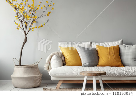 White sofa with grey plaid and yellow pillows against grey wall 118193054