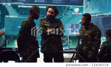 Diverse army officers examining real time data on a hologram, working with high tech holograph in a military command center for surveillance. Gather intelligence to support field troops. Camera A. 118193119