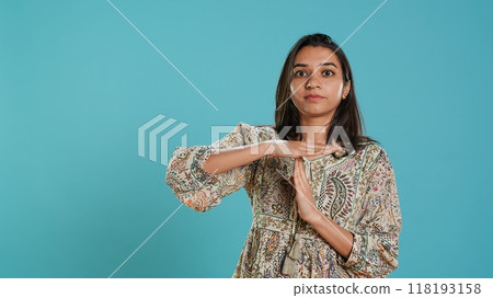 Portrait of assertive indian woman asking for timeout, doing hand gestures, feeling fatigued. Firm person doing vehement pause sign gesturing, wishing for break, studio background, camera A 118193158