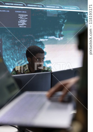Military personnel in a modern command post work on data processing, integrating real time surveillance in strategic planning for a mission. Security protocols for national defense operations. Military personnel in a modern command post work on data processing, integrating real time surveillance in strategic planning for a mission. Security protocols for national defense operations. 118193171