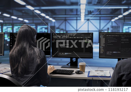 Software developer checking for signs of imminent failure in data center equipment. IT professional working at PC desk to preventing server rows damages, monitoring critical systems Software developer checking for signs of imminent failure in data center equipment. IT professional working at PC desk to preventing server rows damages, monitoring critical systems 118193217