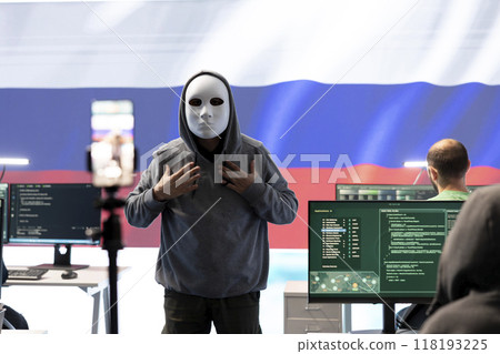 Anonymous hacker expert in a russian hacking high tech office, digital threats and political espionage. Inflicting cyber terror, propaganda and crisis management in information war. Anonymous hacker expert in a russian hacking high tech office, digital threats and political espionage. Inflicting cyber terror, propaganda and crisis management in information war. 118193225