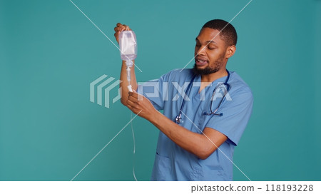 Male nurse holding IV bag, preparing to use it to administer fluids, medications and nutrients directly into patient veins, studio background. Man holding intravenous therapy medical tool, camera B Male nurse holding IV bag, preparing to use it to administer fluids, medications and nutrients directly into patient veins, studio background. Man holding intravenous therapy medical tool, camera B 118193228