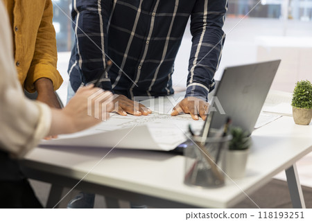 Entrepreneur and real estate agents collaborate on a corporate office planning session, discussing blueprints and investment strategies for leasing or renting a new urban office space. Close up. 118193251