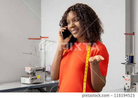 Female dressmaker talking on smartphone with customer managing work and client orders Female dressmaker talking on smartphone with customer managing work and client orders 118194523