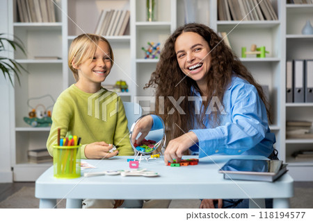 Cute long-haired speech therapist working with a blonde boy, both smiling Cute long-haired speech therapist working with a blonde boy, both smiling 118194577