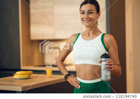 Fit woman enjoying protein-rich drink to support her athletic lifestyle during home workout 118194740