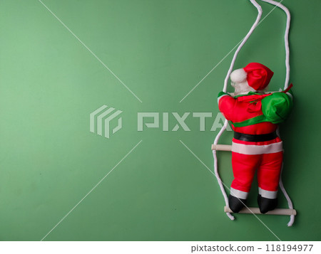 A statue of Santa Claus climbing the stairs on a green background with copy and text space. 118194977