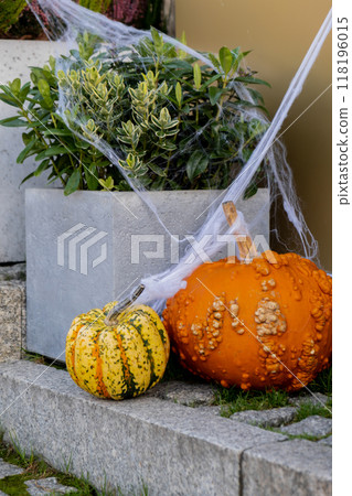 Exterior Beautiful cozy atmospheric halloween pumpkins decorated on porch. Autumn leaves and fall flowers holiday Thanksgiving October season outdoors in city 118196015