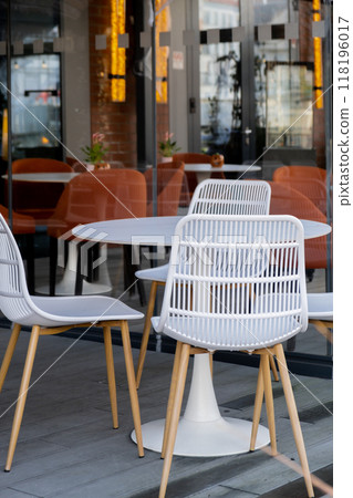 Cozy outdoor cafe restaurant terrace with empty white chairs in autumnal city. Modern lounge outside with relaxed atmosphere. Exterior 118196017