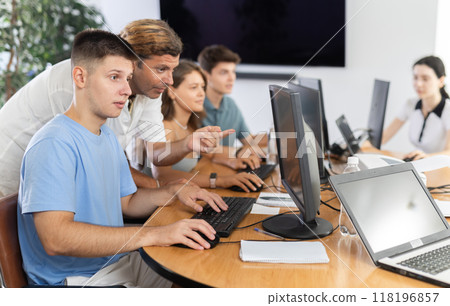 During computer lesson, male teacher helps guy student complete difficult task, During computer lesson, male teacher helps guy student complete difficult task, 118196857