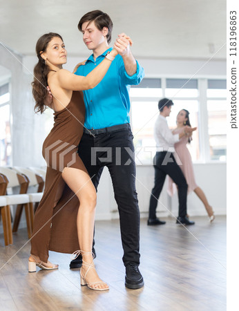 Guy enjoying impassioned merengue with female partner in dance class Guy enjoying impassioned merengue with female partner in dance class 118196863