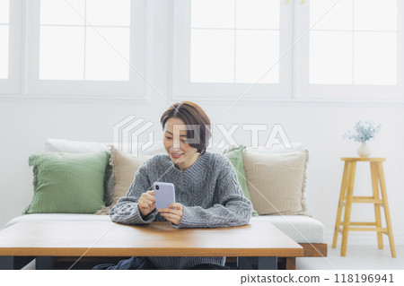 看智能手機的婦女在屋子裡 118196941