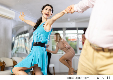 Cheerful young woman practicing vigorous dance at group class 118197011