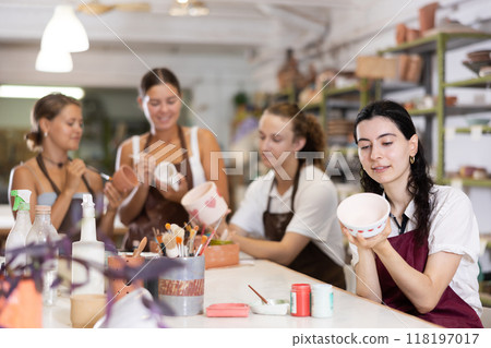 Girl painting with brush on handmade ceramic bowl 118197017