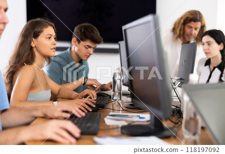 Girl student of computer courses looks at monitor screen, types on keyboard and does work 118197092
