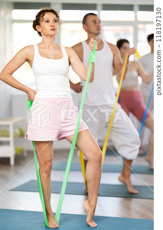 Young woman doing shoulder workout with resistance band in standing positions 118197130