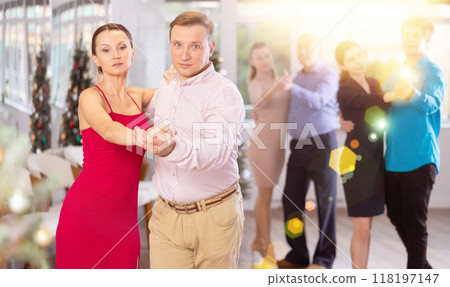 Men and women dancing tango or samba next to Christmas tree Men and women dancing tango or samba next to Christmas tree 118197147