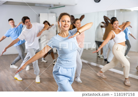Group of active women and men practicing energetic dance in modern dance studio Group of active women and men practicing energetic dance in modern dance studio 118197158